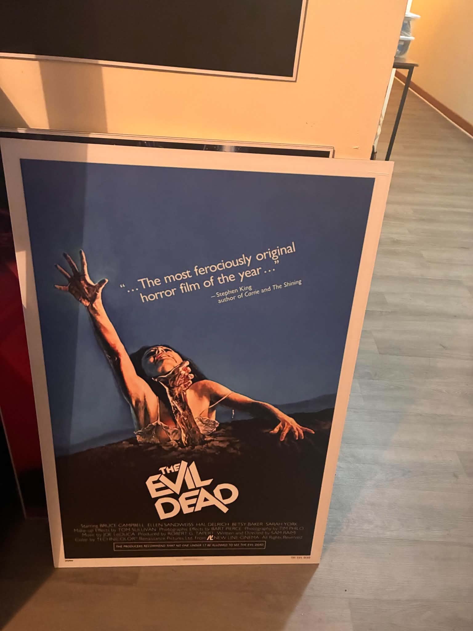 Photo of The Evil Dead original poster print of a woman rising from the grave under a Stephen King review quote
