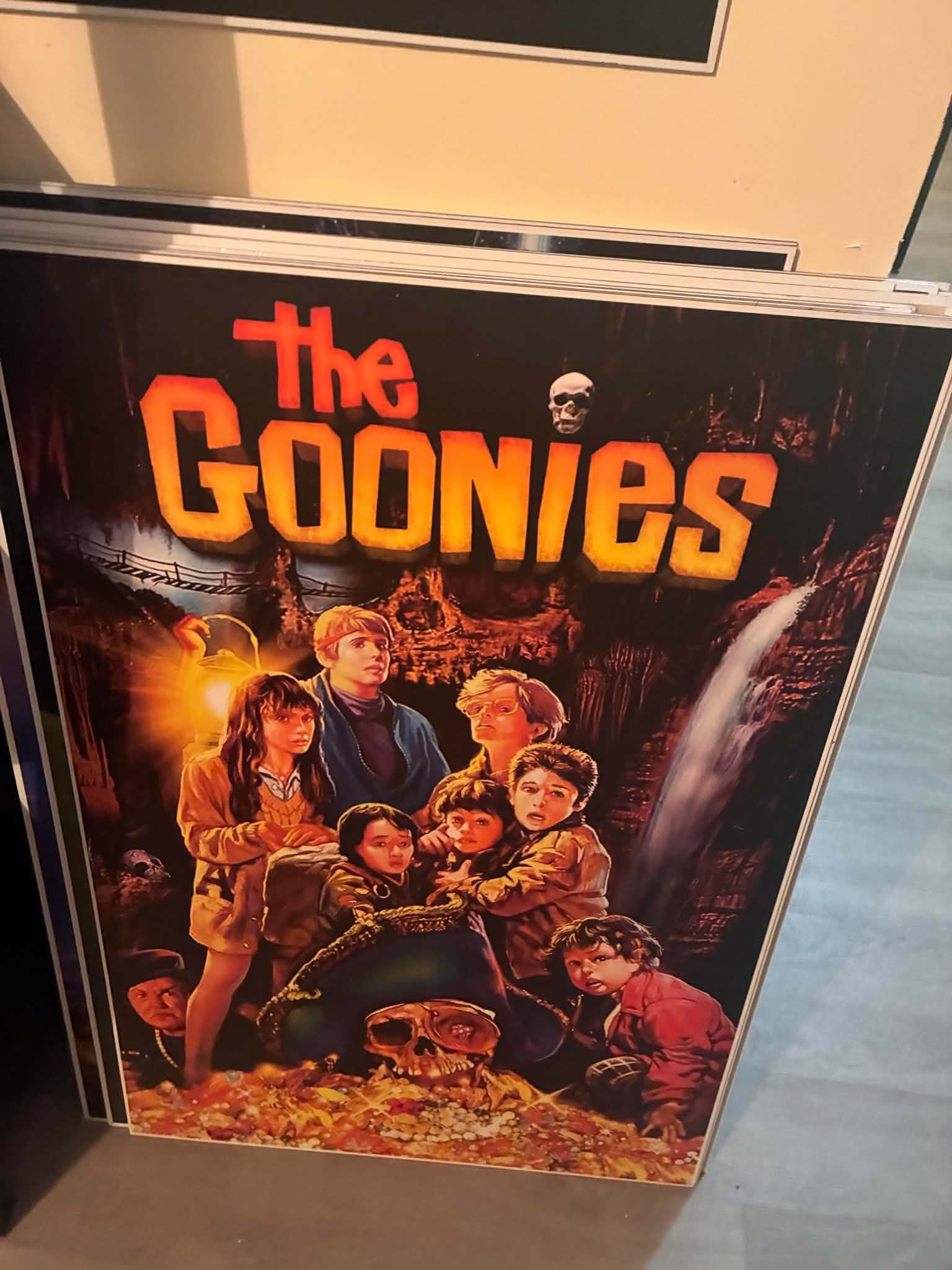 Photo of a The Goonies poster print with the kids discovering the skull and treasure in the cave, painted in blazing orange